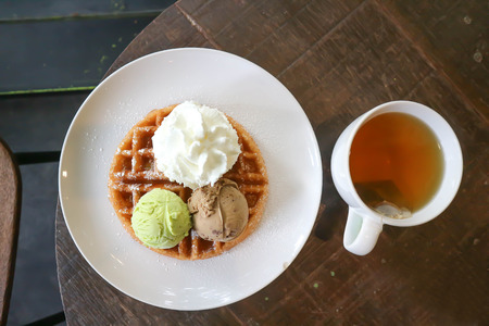 waffle with ice cream topping and hot teaの写真素材