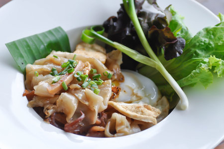Stir fried noodles pork and fried egg on a plate