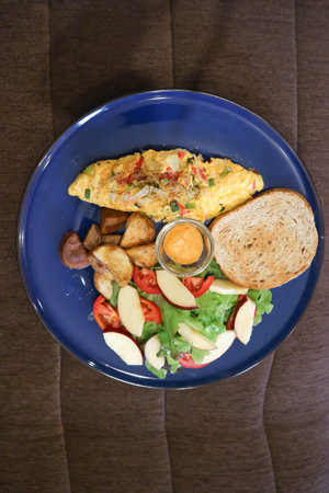 omelette , omelet or scrambled egg with salad and fried potato and dressing