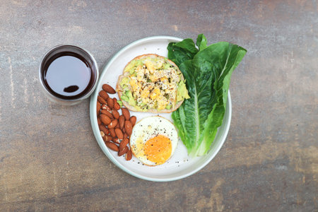 bread with egg and avocado topping with sunny side up egg , lettuce , almond and americano coffee for serveの写真素材