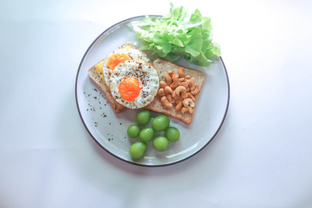 toast or bread with sunny side up egg , cashew nut , grape and lettuce for breakfastの写真素材