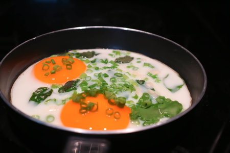 fried egg or sunny side up egg with vegetable topping in a pan or frying pan