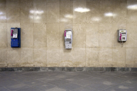 Wall of an underpass with three different telephonesの写真素材