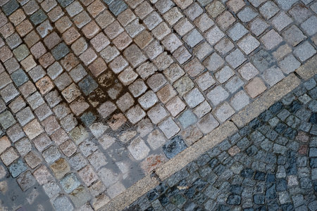 Raindrops are falling in a puddle on a paved streetの写真素材
