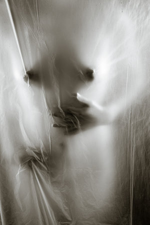 Sexy young woman touching herself behind transparent wet curtainの写真素材