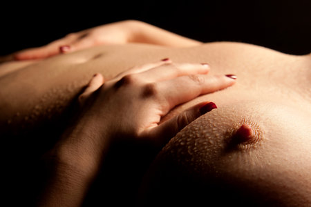 Wet breasts of a young sexy woman in front of black background の写真素材