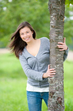 Outdoor portrait of a cute teen behind a tree in summerの写真素材