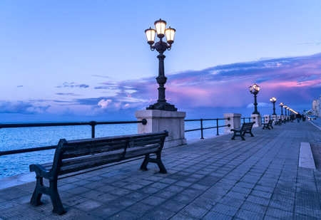Bari seafront at sunset Purple and blue sky landscape panorama. Bench and street lamp near the seaの写真素材