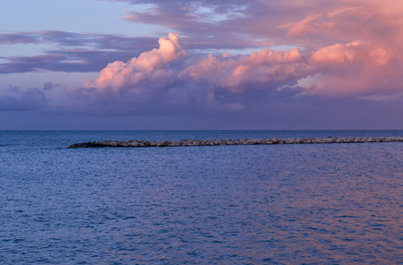 stunning sunset over sea and rocks. Bari seafront coastline. Blue and purple sky and cloudsの写真素材
