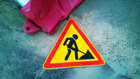 Triangular road sign roadwork lies on the wet ground
