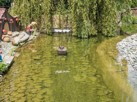 Beautiful artificial pond with figurines of gnomes, cooks and small houses in the park Russia Sochi 06 22 2019のeditorial素材