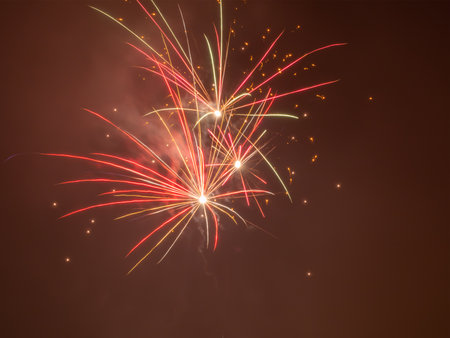 Close-up photo of two bright pink fireworks with orange sparks in a blurred sky