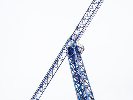 Tall blue tower crane for building houses on a cloudy sky backgroundの写真素材