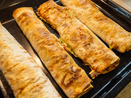 Appetizing baked rolls with a golden crust on a black panの写真素材