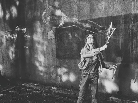 Young girl blows soap bubbles on a wall background. Black and white sceneの写真素材