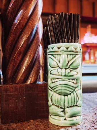 Russia, Sochi 14.03.2020. A glass of tiki with straws for cocktails stands on a counter next to a carved wooden column.のeditorial素材