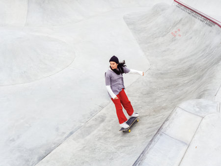 Sochi, Russia - 26 December 2019. Girl in red pants rides a skateboard in the bowl of a skateparkのeditorial素材