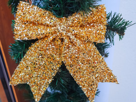 Shiny sequin bow hanging on an artificial spruce branch