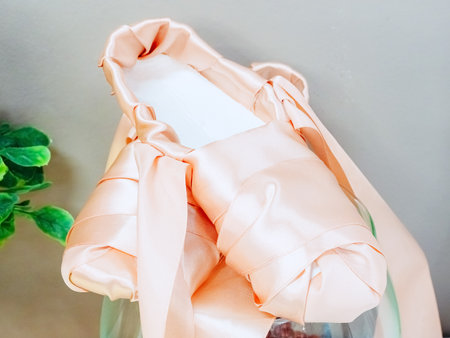 Pointe shoes made of pink satin ribbon against a gray wallの写真素材
