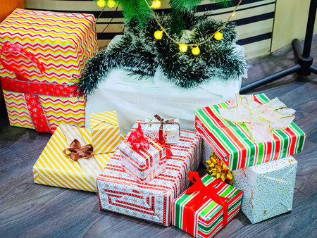 Christmas gifts in boxes with patterned wrapping rewound ribbons lie on the floorの写真素材