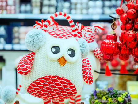 Soft knitted toy white-red owl in fur headphones on a blurred backgroundの写真素材