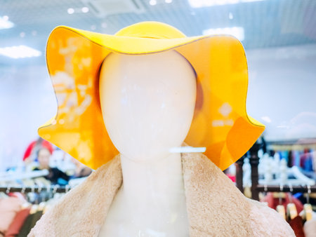 Abstract mannequin head in yellow hat on blurred shop backgroundの写真素材