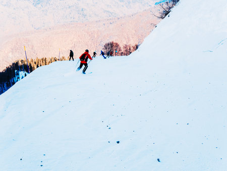 Riders descend along a narrow snow track sprinkled with small pebbles