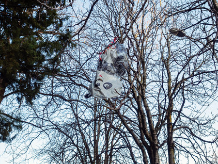 A flying away and deflated panda-shaped balloon hangs on a bare treeの写真素材