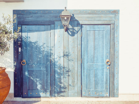 Light blue wooden doors with round golden door handles and a lantern in betweenの写真素材