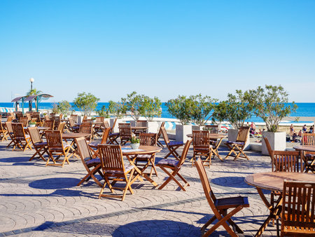 Russia, Sochi 07.06.2020. Street cafe with round wooden tables and chairs on a platform overlooking the seaのeditorial素材