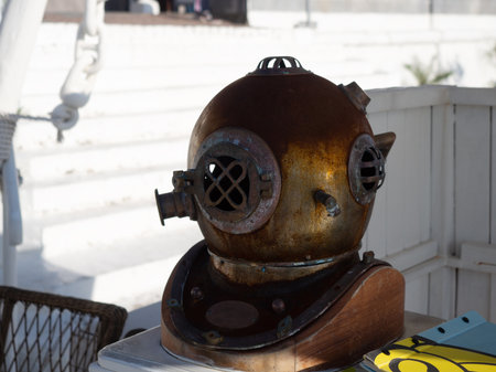 Decorative metal diving helmet on a rack against a background of white wooden wallsの写真素材