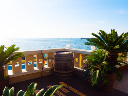Sea view from the balcony of a street cafe with a decorative table from a barrel with a chair and palm trees in potsの写真素材