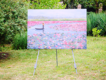 Russia, Tuapse 15.11.2020. A painting depicting a pond with water lilies and a man in a boat stands on a metal tripod in the parkのeditorial素材