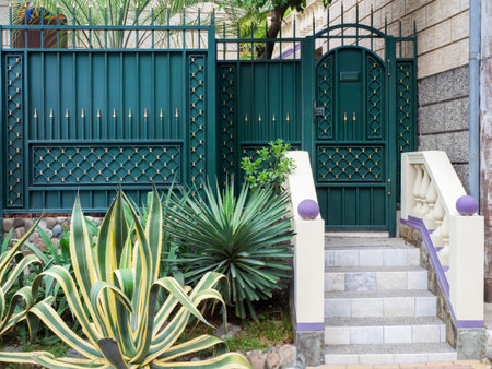 Dark turquoise decorative fence with a gate with marble steps and agave growing in frontの写真素材