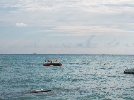 The boat with tourists floats on the sea waves under the sky with cloudsの写真素材