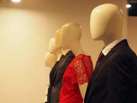 Male and female faceless mannequins in suits and dresses stand in a row in the storeの写真素材