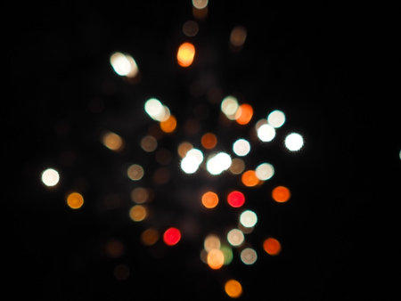 Bright specks of white orange and red bokeh against a dark background. Abstraction backgroundの写真素材