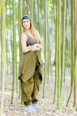 Hip-hop girl stands with folded arms in a green bamboo groveの写真素材