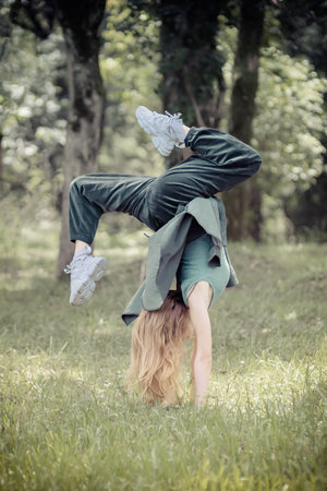 Girl doing a handstand on a green lawn in a park on a summer dayの写真素材