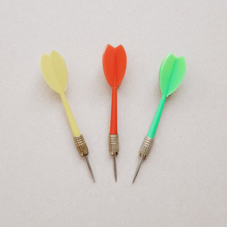 Yellow red and green darts lie on a light background. Closeup photo. Flatlay
