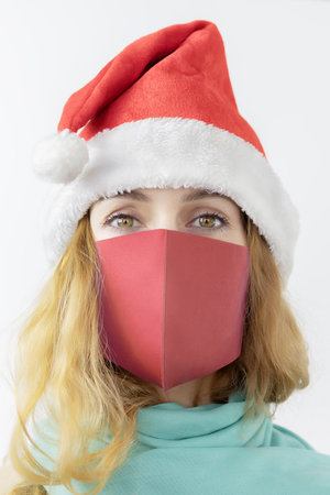 A girl in a Santa hat and a protective mask. Portrait photo. Protected Christmas. Viral Christmas. Holiday posterの写真素材