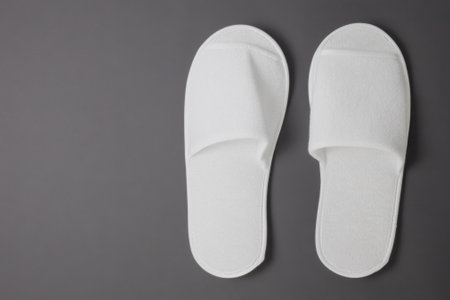 A pair of new terry slippers stand against a gray matte background. For home and hotels. Left place for text and editingの写真素材
