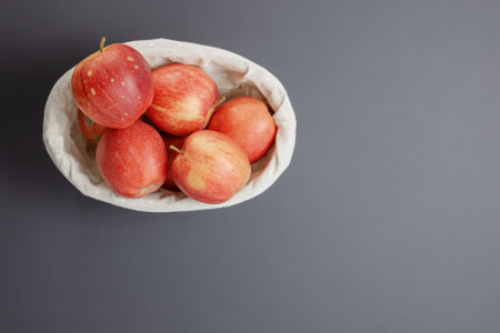 Vase with cloth and beautiful red apples on a matte gray background with empty space for text. View from above.の写真素材