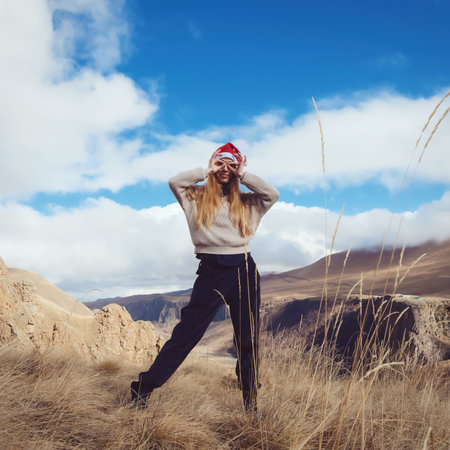 The girl in Santa Claus hat. Made a gesture with her hands funny glasses. Against the backdrop of beautiful nature.の写真素材