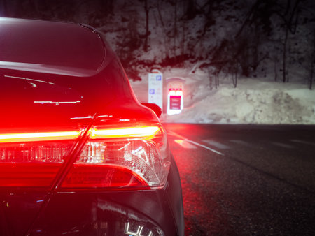 Russia. Sochi. Rosa Khutor 24.01. 2021. Included rear light fragment of the car. In the parking lot. Against the background of the forest and illuminated signs. Soft focusのeditorial素材