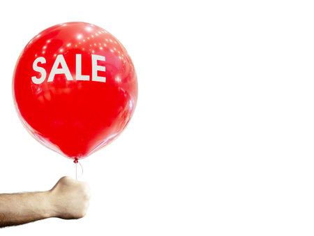 A mans hand holds a red inflatable ball with the inscription sale. On an isolated white background.の写真素材