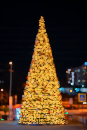 A large Christmas tree stands in the middle of the city at night. Defocused image with bokeh effect....