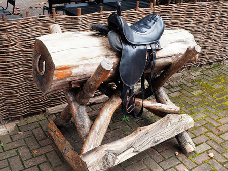 Black saddle on a round log with a horseshoeの写真素材