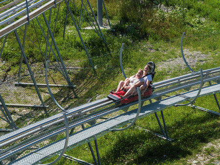 Russia, Sochi 04.08.2019. Mom and daughter joyful ride on Rodelbahn. Rosa Khutor. Height 1100 mのeditorial素材