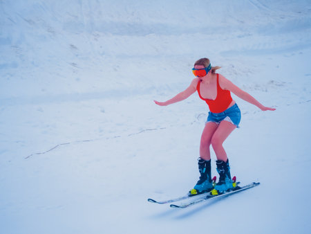 Russia, Sochi 11.05.2019. A girl skier in denim shorts and an orange T-shirt plucked up courage and gained speed. Krasnaya Polyanaのeditorial素材